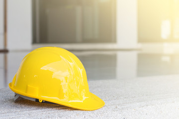 Wall Mural - The yellow safety helmet put on the blueprint at construction site with crane background