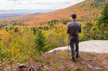 young man standing at panoramic lookout on megantic mount in canada, enjoying autumn colours