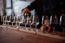 Row Of Wine Glasses Being Poured With Multiple Types Of Wine