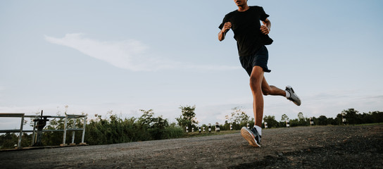 Young man running on a rural road during between the summer on vacation, run for health according nature, Early in the morning.