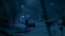 Night Time Snowfall In A City On Peaceful, Calm, Tranquil Evening During Winter Holidays Season On Streets Of Residential Suburbs With Houses, Lights And Cars Covered With Snow By Thick Snowflakes