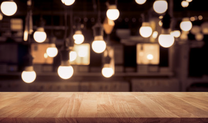 Wall Mural - Wood table top on blurred of counter cafe shop with light bulb background.For montage product display or design key visual