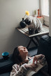 © BONNINSTUDIO/Stocksy - Woman with a book and her cute cat at home.