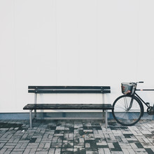Old Bike And Bench In Front Of The White Wall