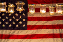 Illuminated Candle Lights Hanging Against American Flag At Night