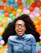 Young African Woman Playing With Many Colorful Balloons.