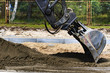 Construction works. Excavator evens out the ground.