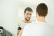 © auremar - young man trying shirt on in front of mirror
