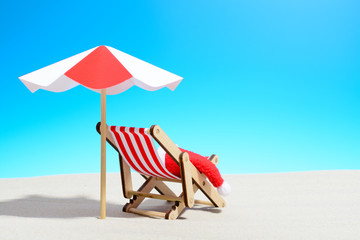 Wall Mural - Merry Christmas on beach concept. Lounge chair with umbrella and Santa hat