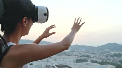 Wall Mural - Woman watching with VR on the roof top