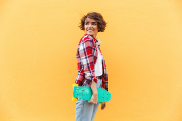 Smiling young teenage girl holding skateboard