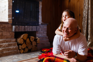 Wall Mural - grandfather and granddaughter sitting at home near the fireplace and hugging