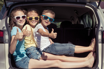 Happy brother and his two sisters are sitting in the car at the day time