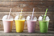 Sweet smoothie in plastic cups on grey wooden table