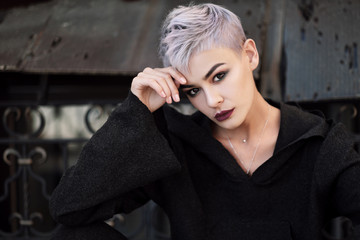 Young beautiful fashion girl shooting outdoors near brick wall at house