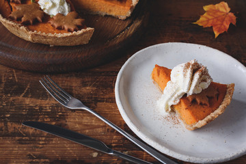 Wall Mural - Pumpkin pie with whipped cream and cinnamon on white plate. Horizontal