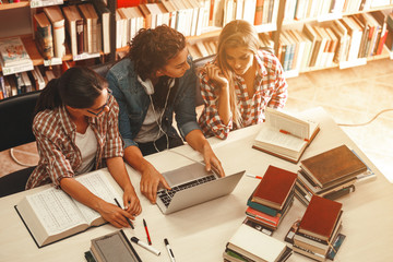 Wall Mural - Group of female students study in the school library.Learning and preparing for university exam.