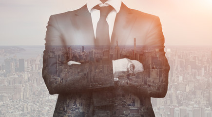 Double exposure of success business man with arms crossed and city in background. Concept businessman lifestyle