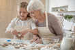 Cheerful grandchild making cookies with granny