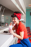 Stylish rockabilly/pin up girl enjoying milkshake at bar. Stock Photo
