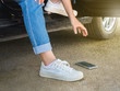Women picking up smart phone that fall on the floor while stepping down from the car
