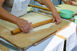 Elderly woman hands rolling out dough with rolling pin on a wooden cutting board. Concept - benefits of cooking at home, active life in old age.