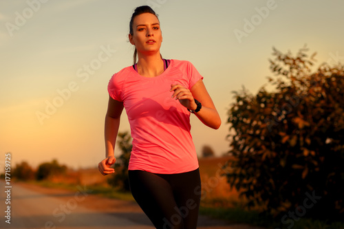 Zdjęcie XXL Sportowy kobieta bieg na wiejskiej drodze podczas zmierzchu.
