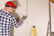 © artursfoto - Construction worker holding gypsum board. Attic renovation. Installation of drywall