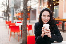 Young Woman Drinking Coffee With Her Cellphone At A Cafe