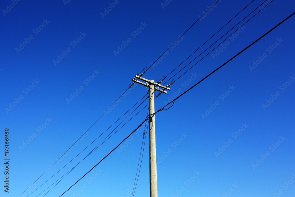 Telephone pole with vibrant blue sky.