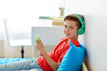 Canvas Print - happy boy with smartphone and headphones at home