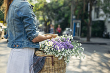Woman Walking In A City Carrying Basket Full Of Flowers