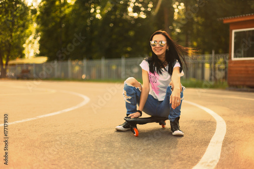 Plakat Lato, dziewczyna w parku jedzie na deskorolce