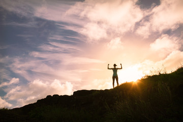 Winning and active lifestyle. Young confident woman flexing on top a mountain edge. 