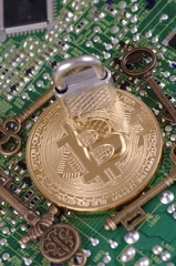 Wall Mural - Golden plated bitcoin with keys and padlock on a printed circuit board.