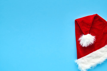 Wall Mural - Christmas card. A bright red Santa Claus hat lies folded on a blue background. Background for your text and design                               