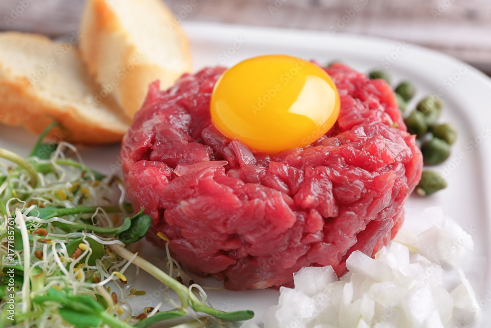 Delicious steak tartare with yolk on plate, closeup