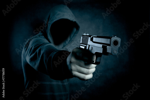Fotomural Hooded man with a gun in the dark
