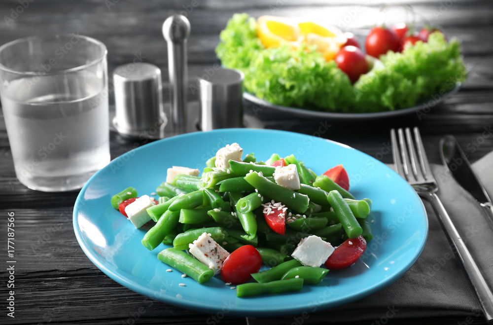 Plate with delicious green beans salad on wooden table
