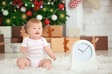 Wall Mural - Adorable baby with clock in decorated room. Christmas countdown concept