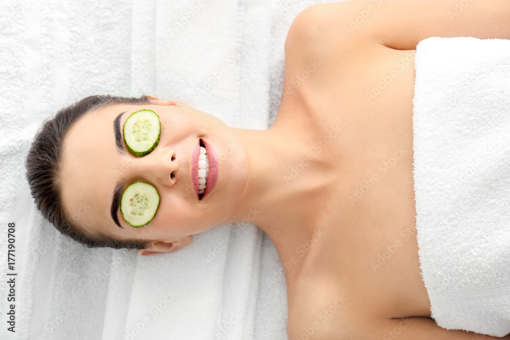 Young woman with cucumber slices in spa salon