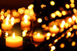 Burning candles and Christmas lights on piano, closeup