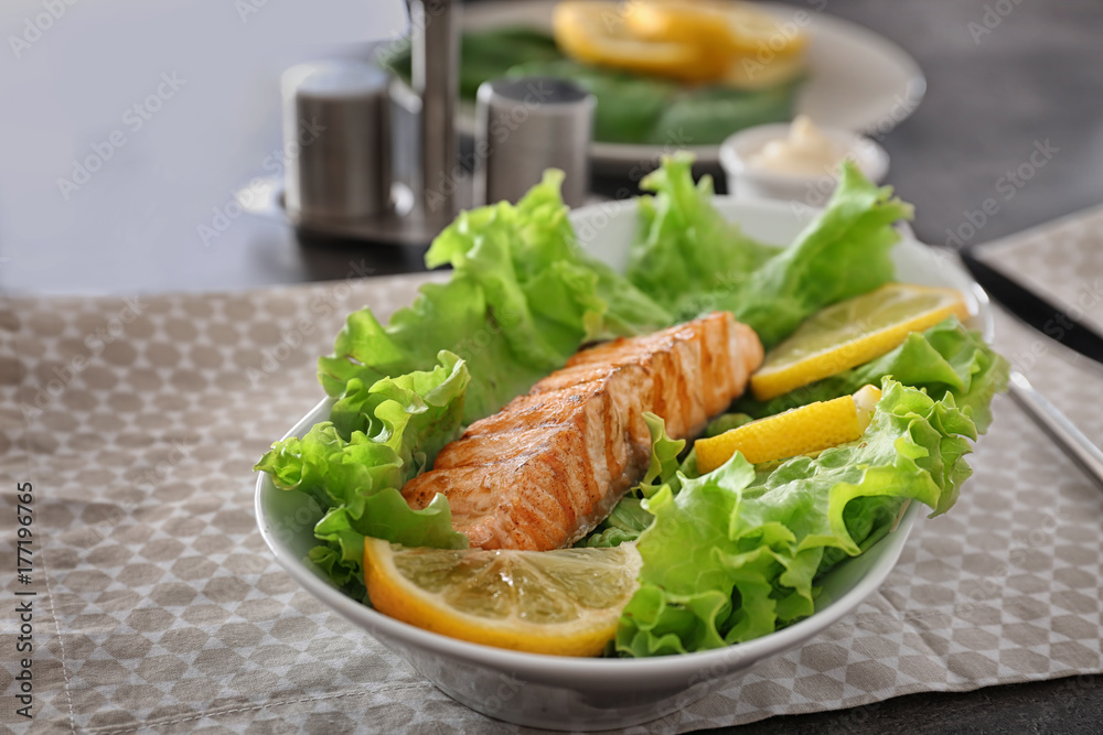 Plate with slice of delicious salmon on table