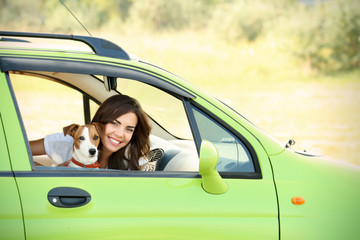 Canvas Print - Beautiful young woman with cute dog in car