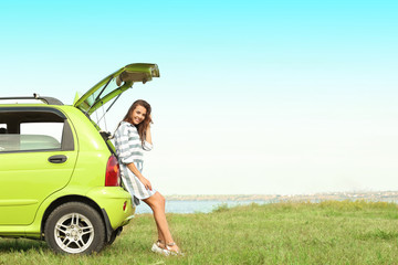 Canvas Print - Beautiful young woman sitting in car trunk outdoors