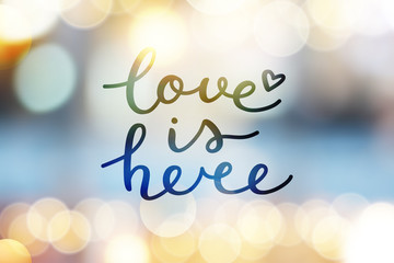 Poster - love is here lettering, vector handwritten text on blurred lights