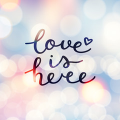 Wall Mural - love is here lettering, vector handwritten text on blurred lights