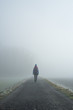 © tomasmikula/Stocksy - Girl with bag standing on the road in the foggy morning