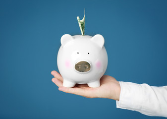 Poster - Young man with piggy bank on color background