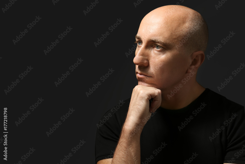 Bald man in t-shirt on black background